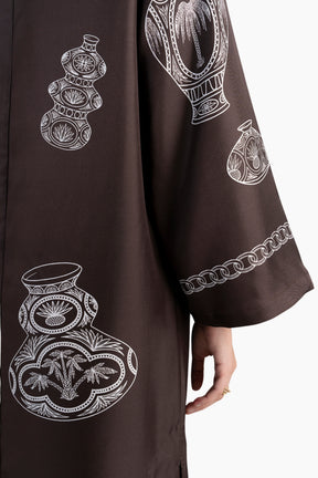 Brown garment with white embroidered designs on a white background