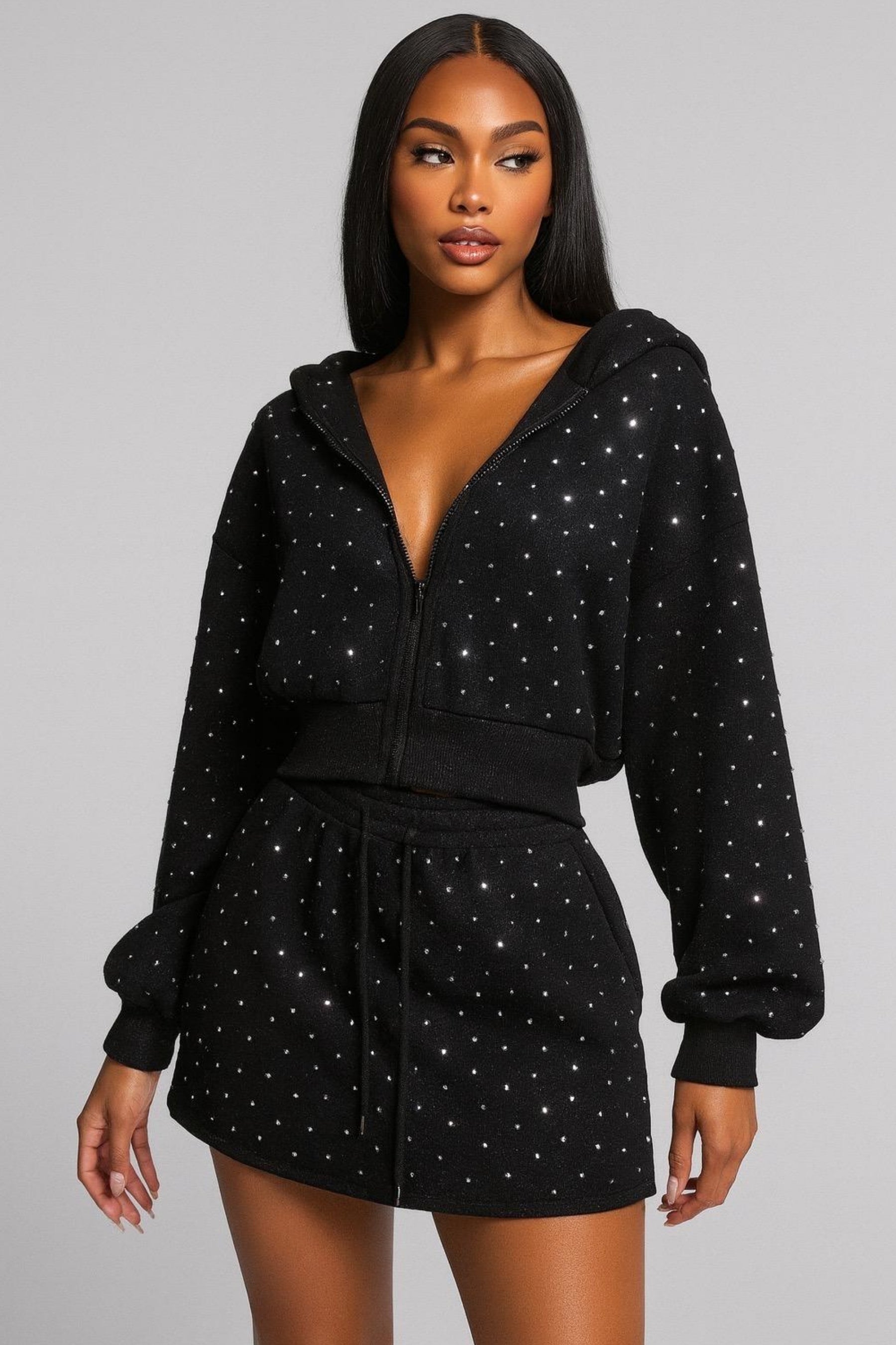 Woman wearing a black hoodie and skirt set with star patterns on a gray background