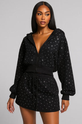 Woman wearing a black hoodie and skirt set with star patterns on a gray background