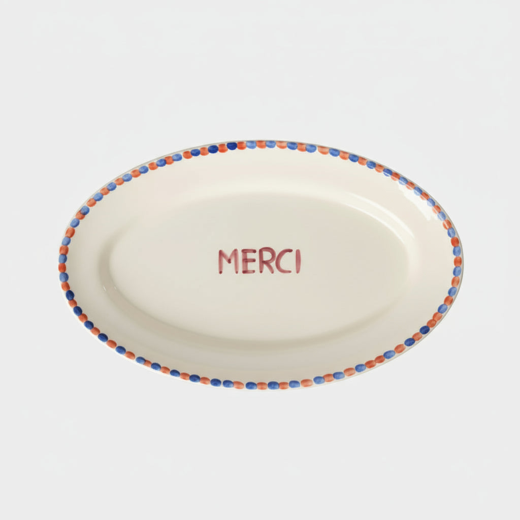 Round ceramic plate with 'MERCI' text and colorful rim 