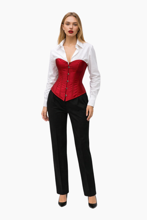Woman wearing a red corset over a white shirt with black pants on a white background