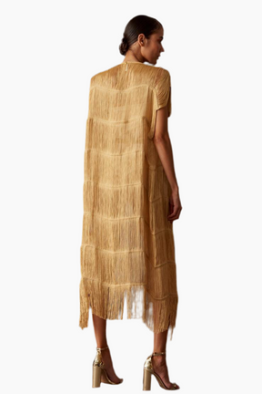 Woman wearing a gold robe with fringe/tassels details 