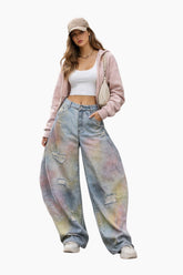 Woman wearing a pink jacket, white top, and tie-dye jeans on a white background