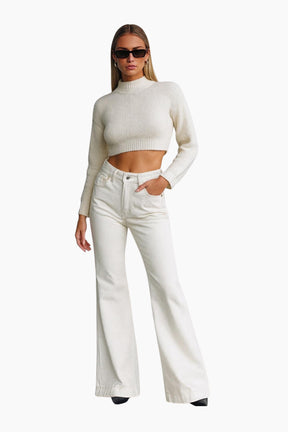 Woman wearing a white sweater and white pants on a white background