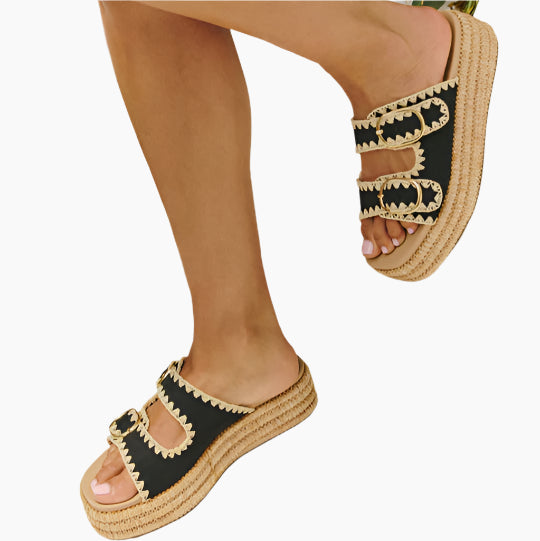 Black sandals with beige straps and sole worn by a person 