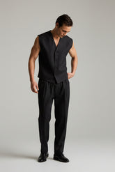Man wearing a black sleeveless vest and pants on a plain background