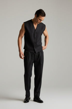 Man wearing a black sleeveless vest and pants on a plain background