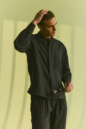 Man wearing a black outfit against a light green background