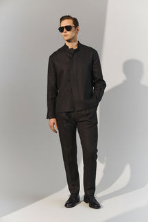 Man wearing a black outfit against a green background