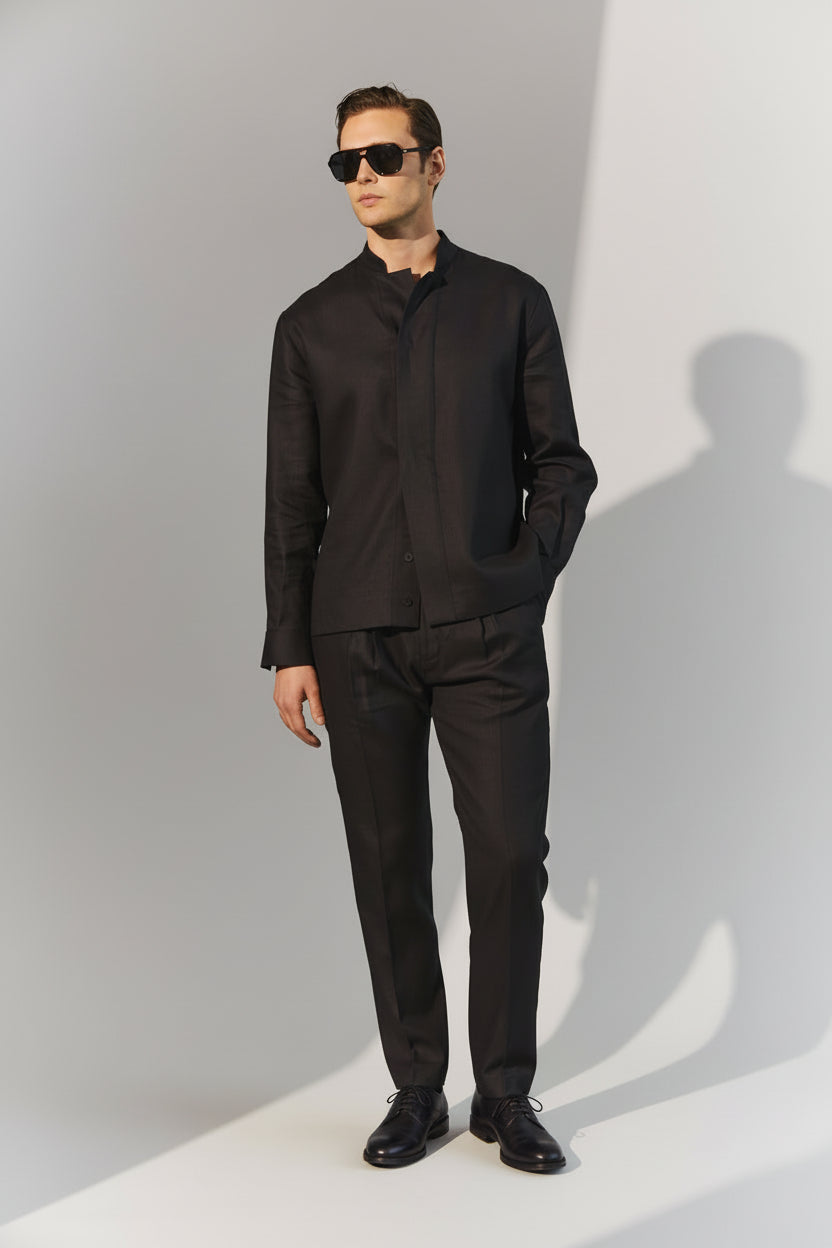 Man wearing a black outfit against a green background