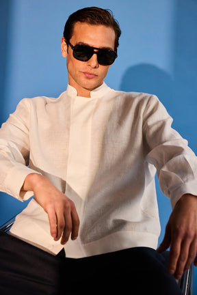 Person wearing a white shirt and sunglasses against a blue background