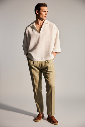 Man wearing a beige shirt and light brown pants against a plain background