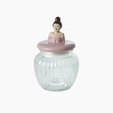 Glass jar with a decorative lid featuring a figurine