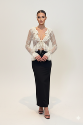 Woman wearing a lace top and black skirt on a white background