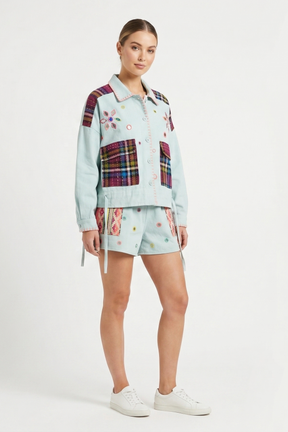 Woman wearing a light blue plaid outfit with a patterned shirt and shorts on a white background
