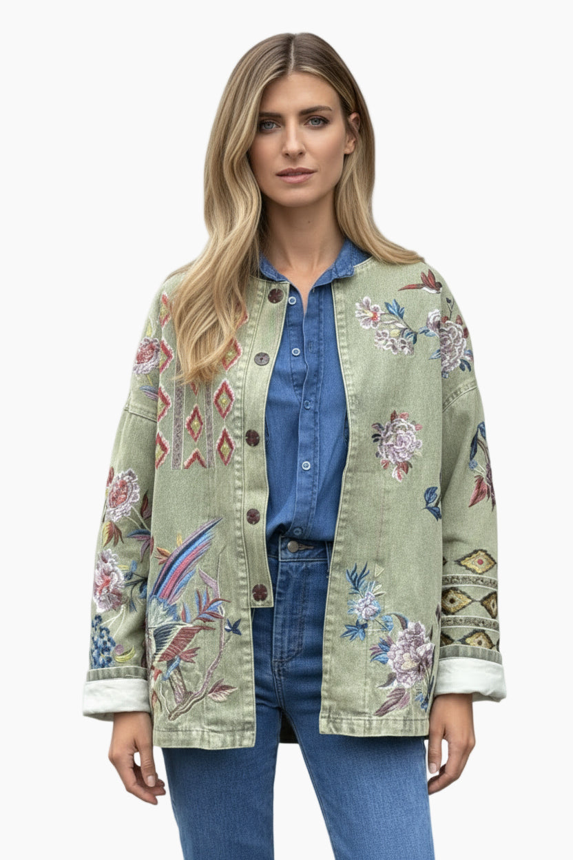 Woman wearing a green embroidered jacket over a blue shirt and jeans 