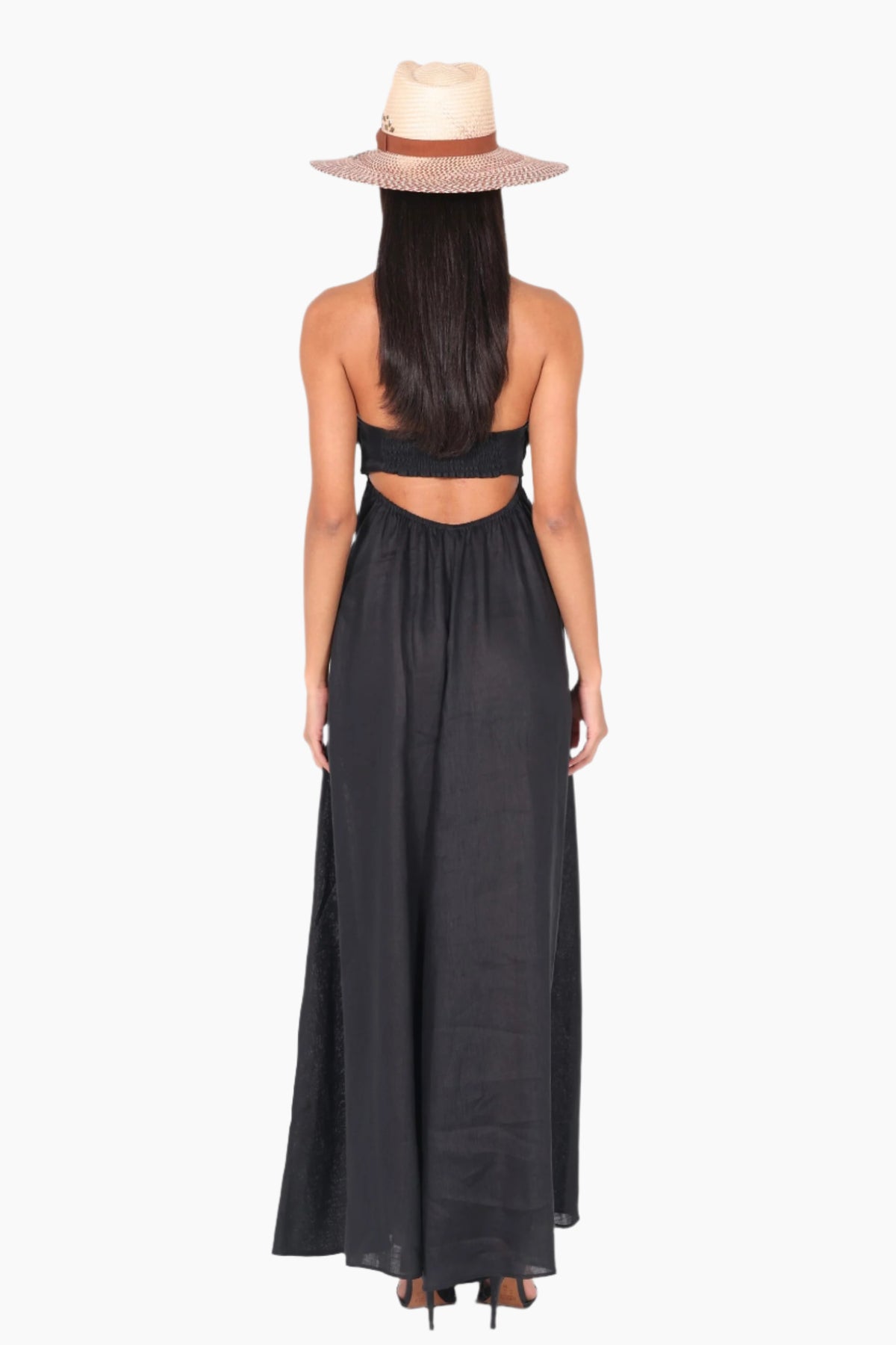 Woman wearing a black halter neck dress with cut-out design and a straw hat 