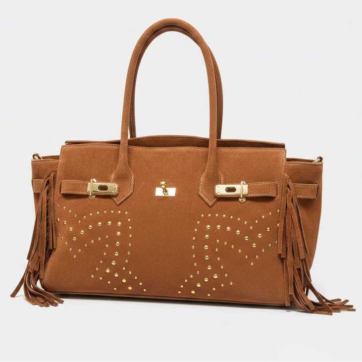 Brown leather handbag with gold studs and fringes on a light gray background