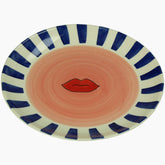 Ceramic plate with blue and white striped rim and red lips design 