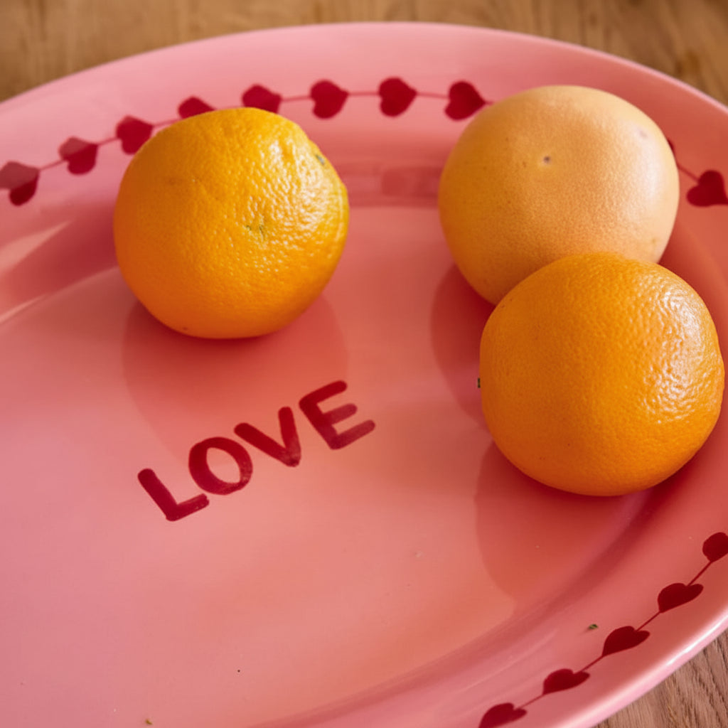 Pink plate with 'LOVE' and three oranges 