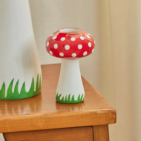 Mushroom-shaped vase with red polka dot cap on a wooden surface