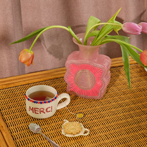 Pink vase with tulips with a cup of tea and biscuit.