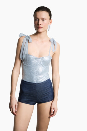 a light blue bodysuit combines shimmering sequins with delicate tulle shoulder ribbons paired with a navy short.