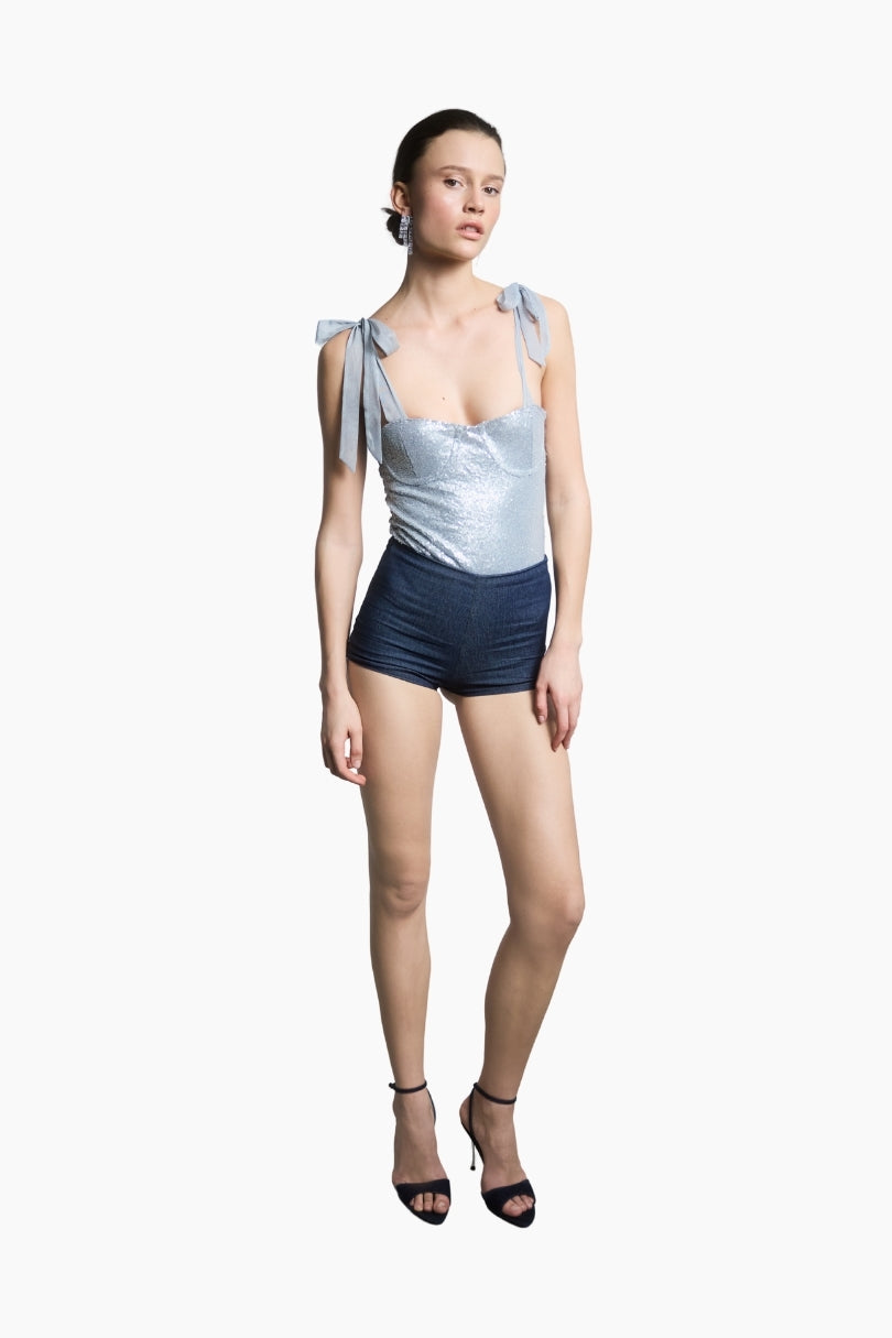 a light blue bodysuit combines shimmering sequins with delicate tulle shoulder ribbons paired with a navy short.