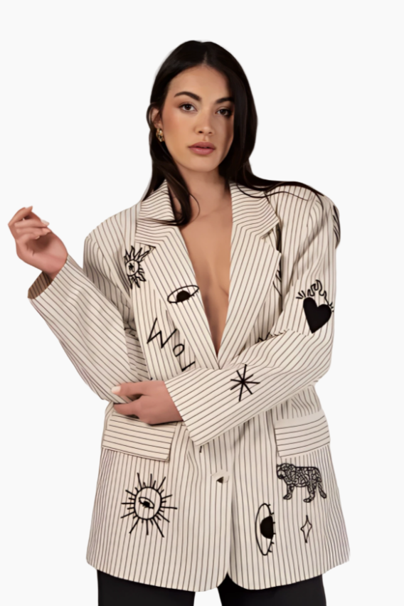 Woman wearing a cream-colored blazer with black embroidered designs 