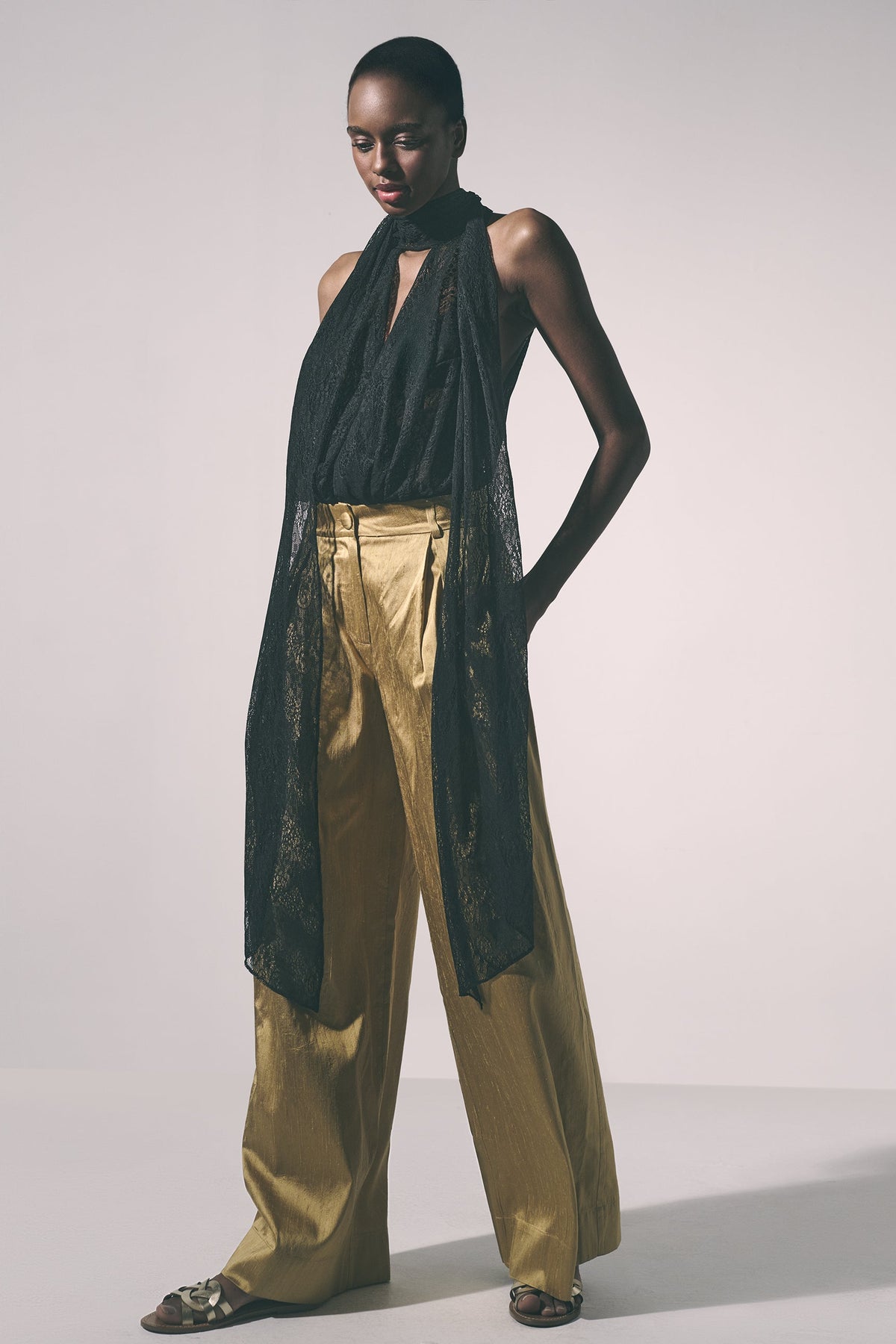 Woman wearing a black lace top and gold pants 