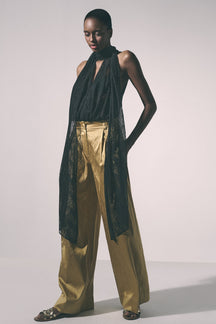 Woman wearing a black lace top and gold pants 