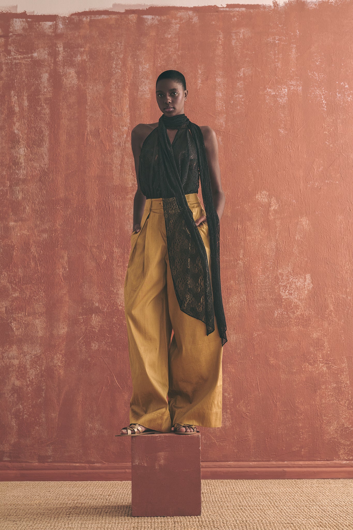 Woman wearing a black lace top and gold pants 
