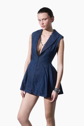 model wearing a Structured denim mini dress with sharp shoulder pads and a bold blazer neckline, featuring a flared hem.