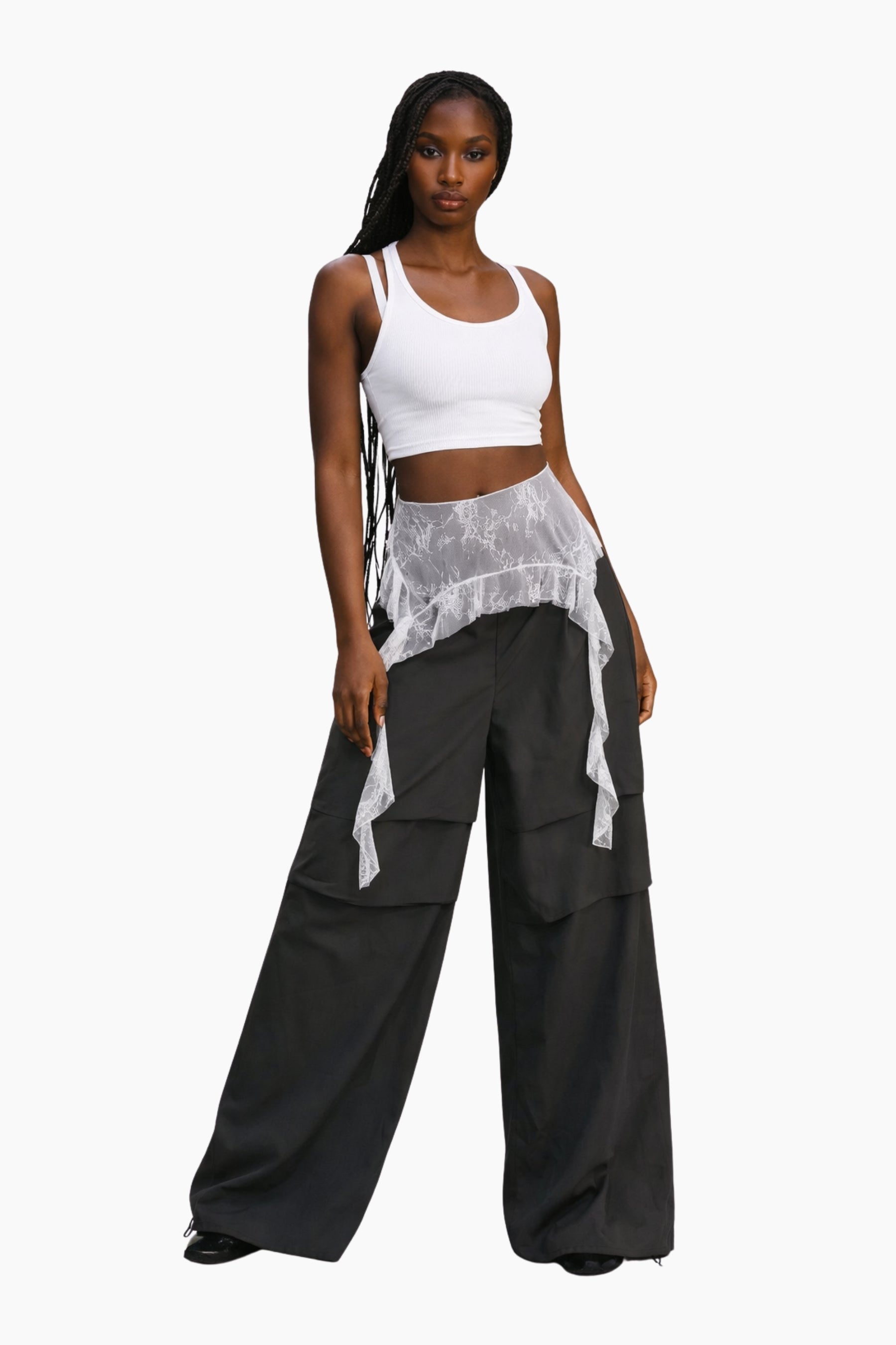 Woman wearing a white top and black pants with sheer panels on a white background