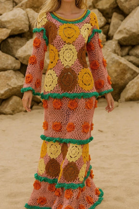Person wearing a colorful crochet dress with floral patterns against a rocky background