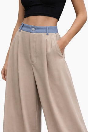 Beige wide-leg pants with a blue belt and black top on a white background
