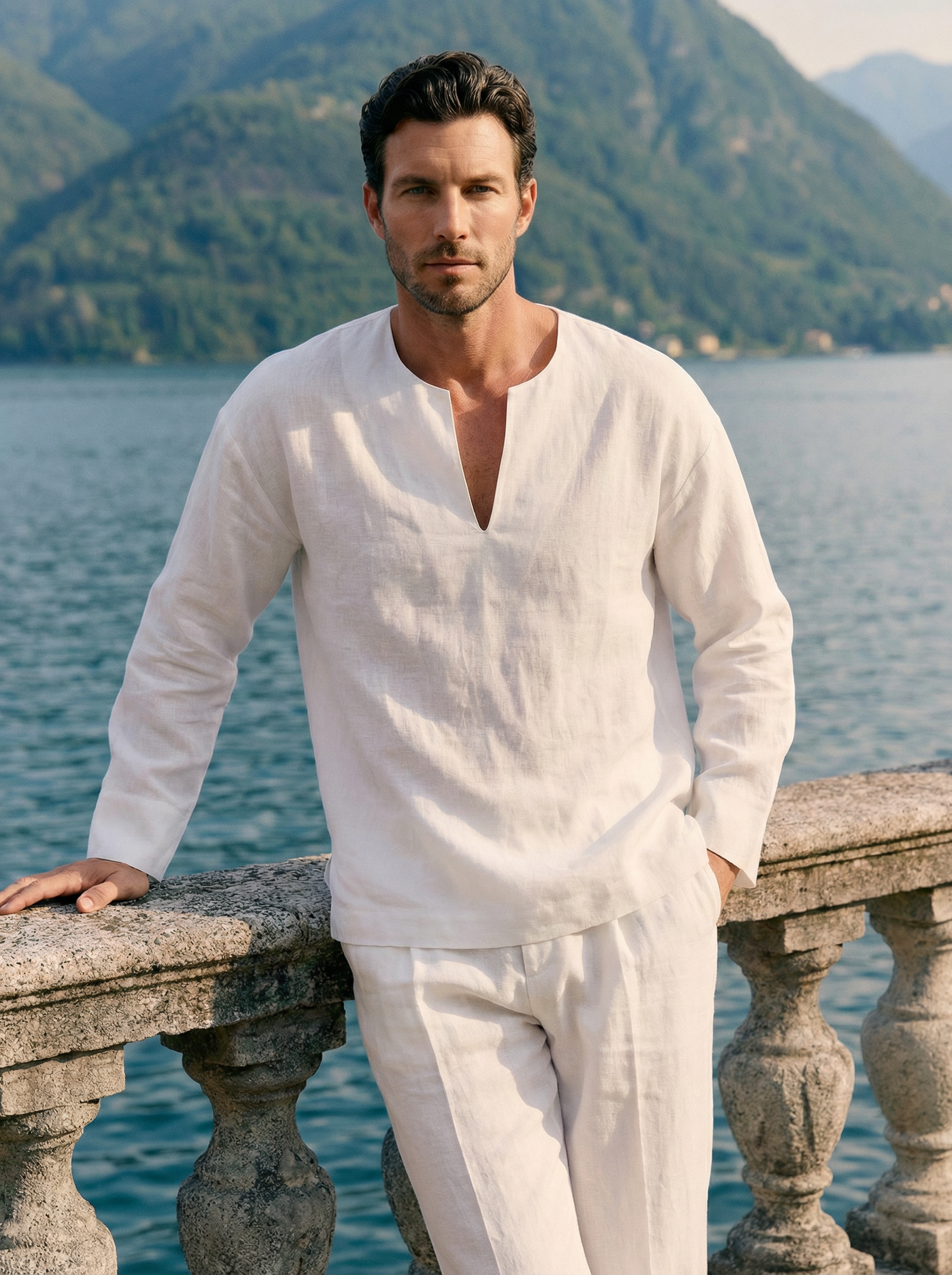 Man in a white outfit standing by a scenic lakeside with mountains in the background