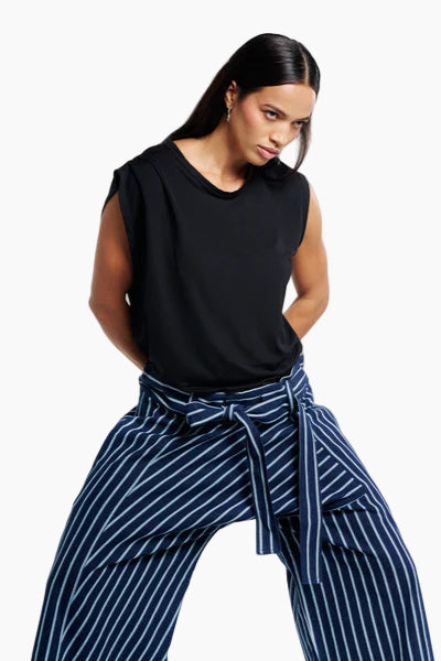 Woman wearing a black sleeveless top and blue striped pants on a white background