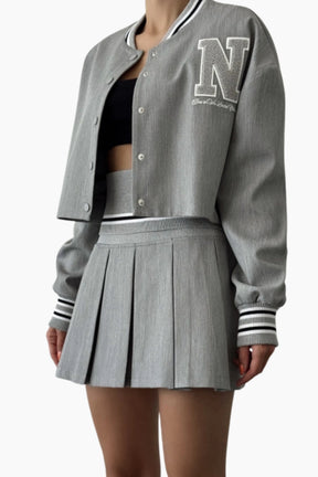 Gray varsity jacket with 'N' logo and pleated skirt 