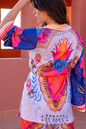Woman wearing a colorful kimono-style outfit with abstract patterns and 'El Amor' text.