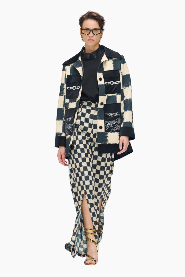 Person wearing a patchwork coat and skirt with a white background