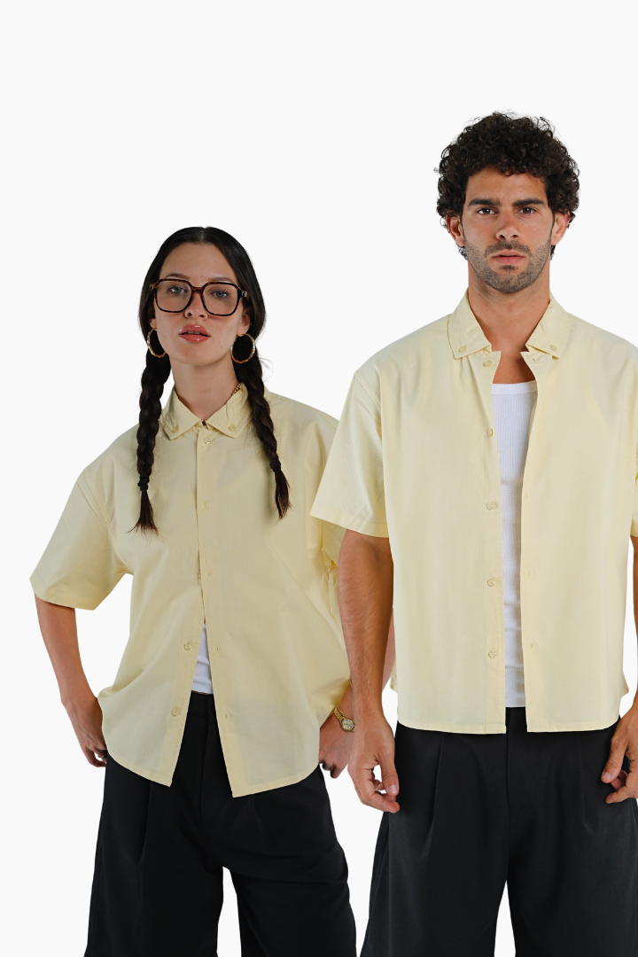 Two people wearing matching light yellow short-sleeve shirts and black pants 