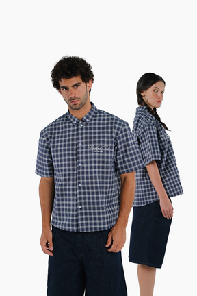 Two people wearing matching blue and white checkered shirts 