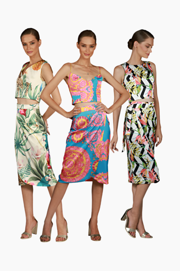 Three models wearing colorful patterned long skirts with matching tops