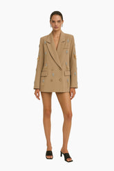 Woman wearing a beige blazer with floral embroidery 