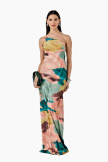 Woman wearing a colorful floral dress. Relaxed-fit asymmetrical one-shoulder dress with a side slit closed by buttons.