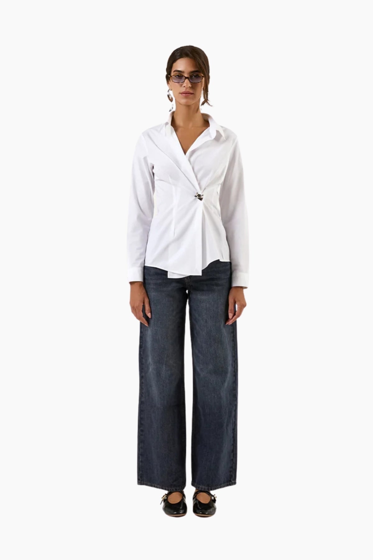 Woman wearing a white blouse and dark jeans on a white background