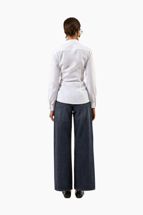 Person wearing a white shirt and dark blue jeans 