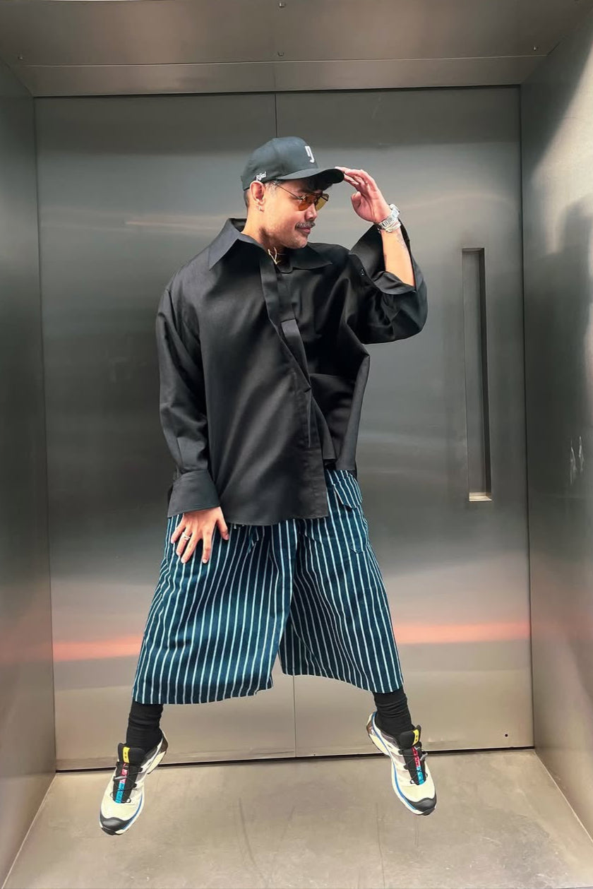 Person wearing a black outfit with striped pants in an elevator
