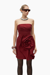 Woman wearing a red strapless dress with a large floral detail